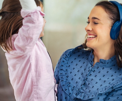 Lachende Frau mit Kopfhörern und ihrem Kind