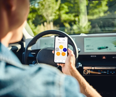 Person im E-Auto mit SENEC.App auf Smartphone